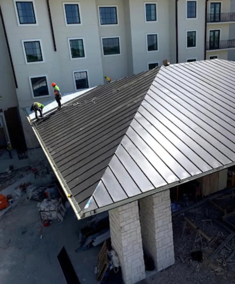 Crew installing standing seam metal roof panels on a commercial project in Marshall